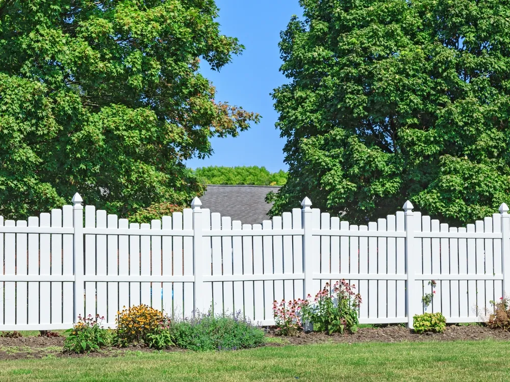 A white scalloped picket fence in front of a planted cottage-style garden bed - Fencing and Landscaping Experts, fencing and landscaping contractors in the Upper North Shore