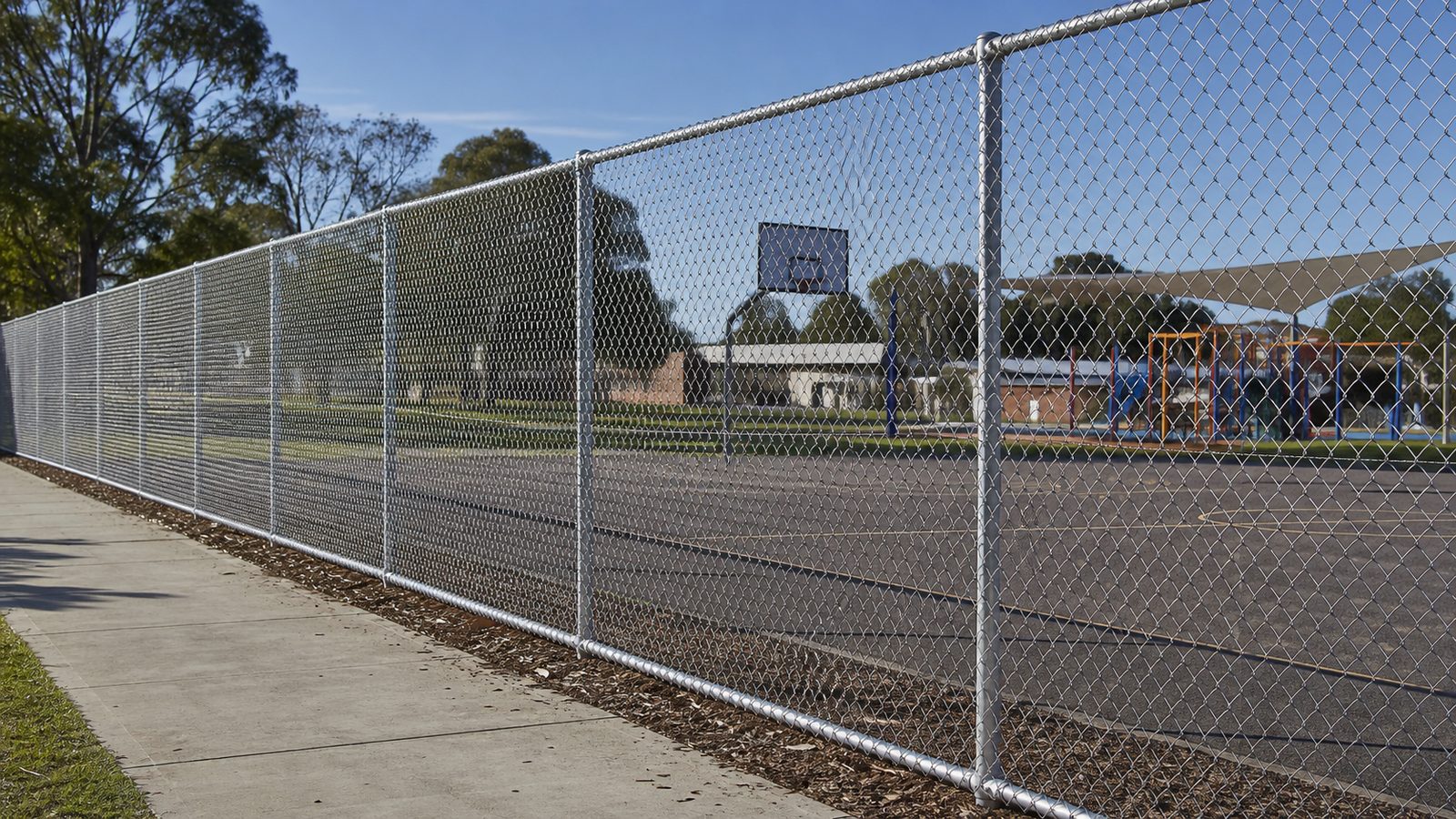 Tall chain wire mesh fencing around a school playground and basketball court